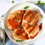 4 pork chops on a white dish with blue napkin