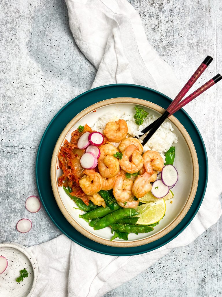 Healthy shrimp rice bowl with kimchi and chopsticks