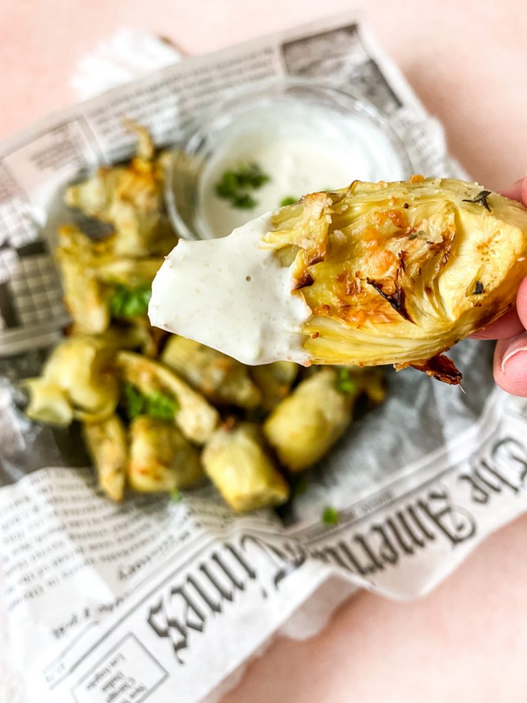 artichokes dipped in sauce with newspaper background