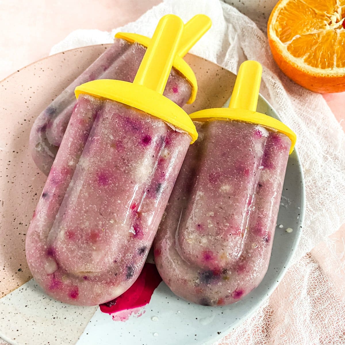 3 popsicles on a plate with an orange slice