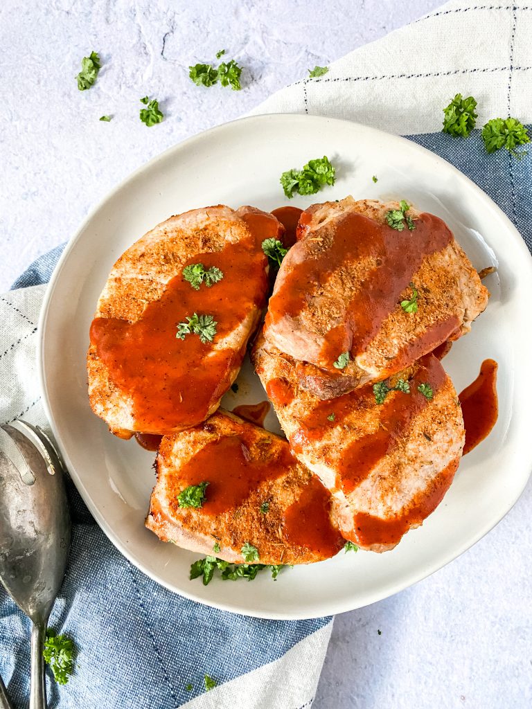 4 pork chops on a plate with bbq sauce 