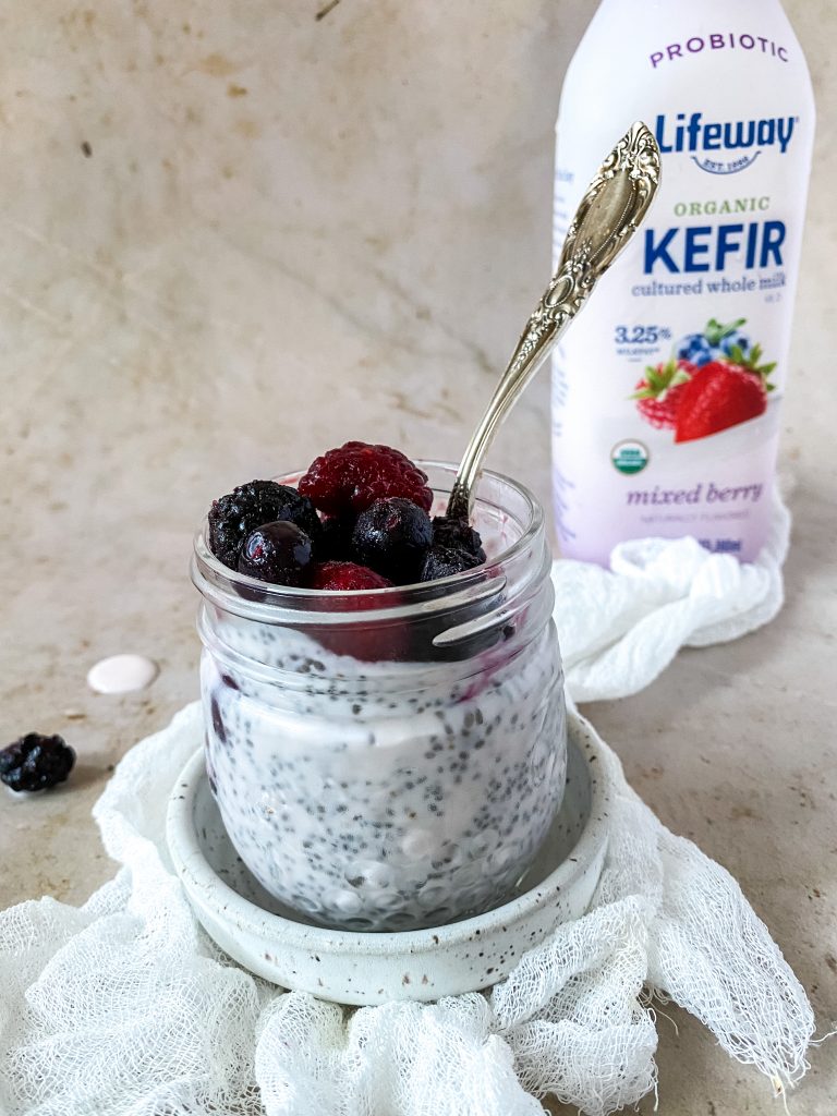 chia pudding in a glass jar with a bottle of kefir behind it. 