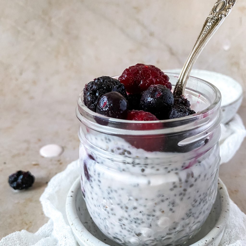 a glass jar full of berry chia pudding with a vintage spoon
