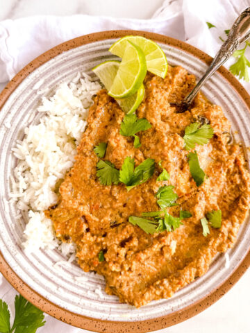 a bowl of black bean curry on rice with lime