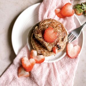 pancakes topped with strawberries with a pink napkin
