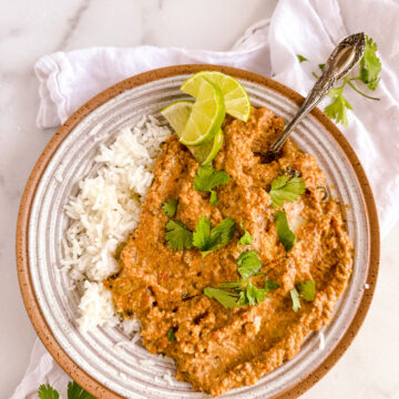 a bowl of curry soup with rice and lime