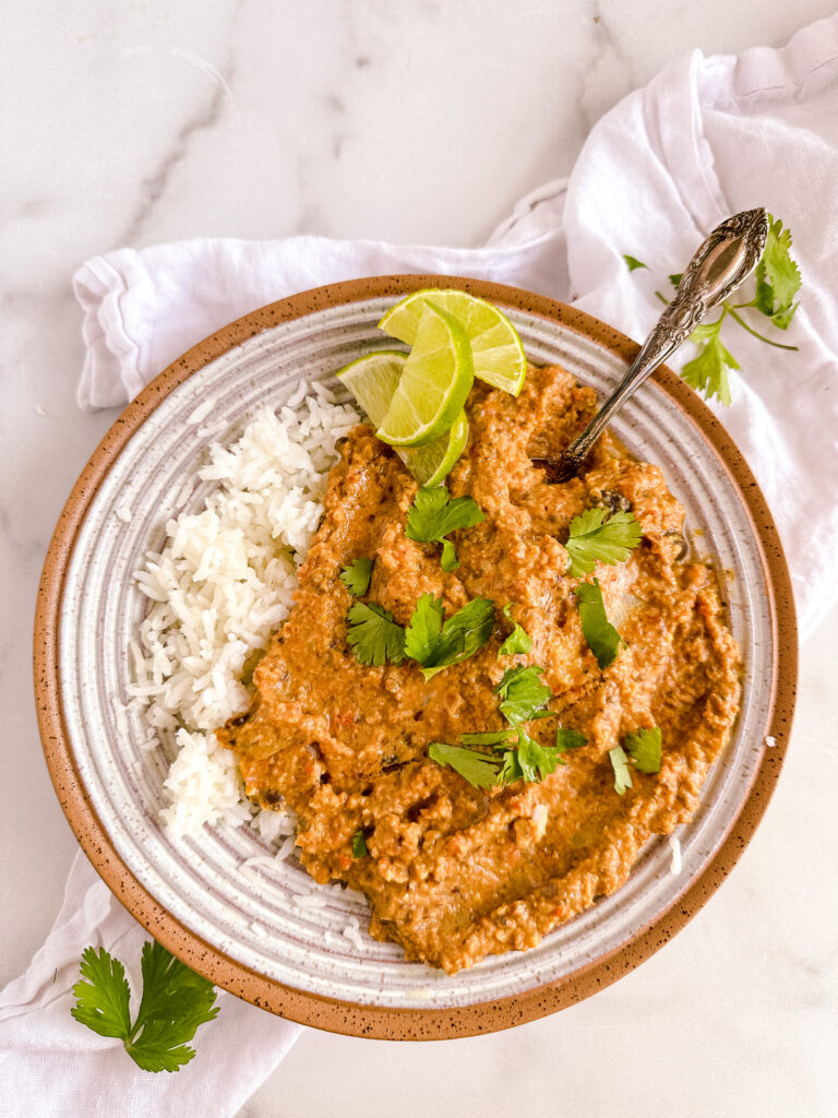 a bowl of curry soup with rice and lime