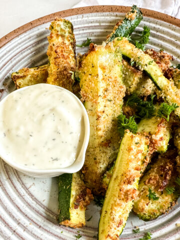 a bowl of air fryer zucchini with ranch dipping sauce