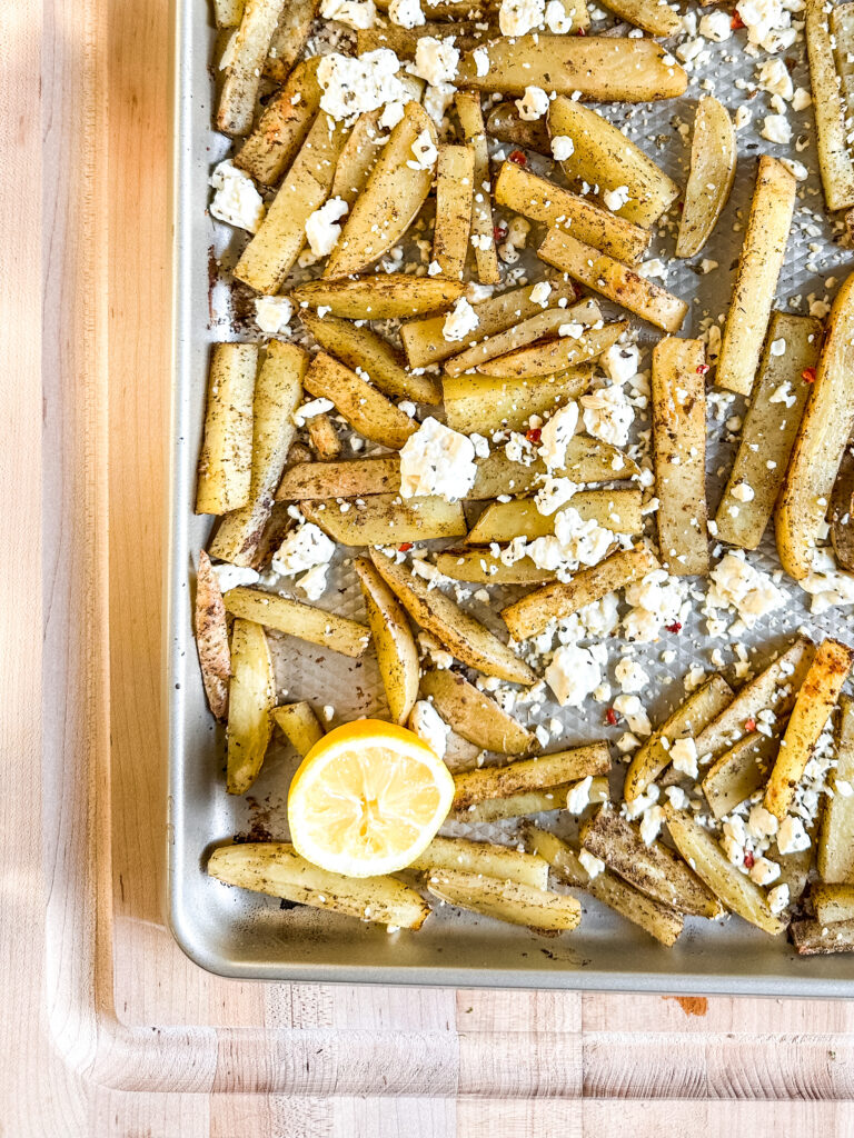 A sheet pan of zaatar fries on a butcher block