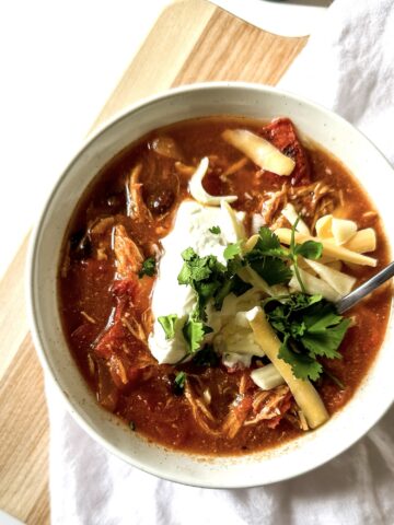 a bowl of enchilada soup topped with greek yogurt