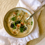 a bowl of chicken soup on a white napkin