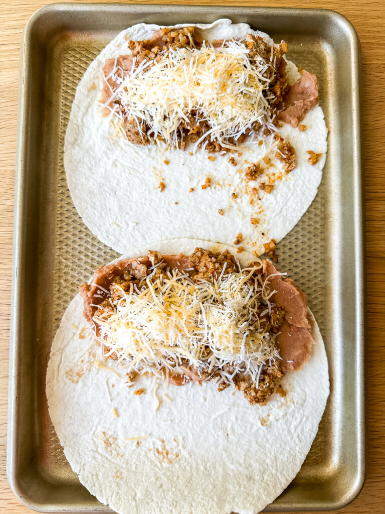 filling tortillas with beef, beans, and cheese