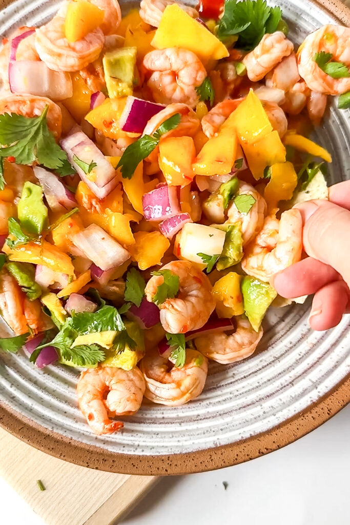 a bowl of mango, shrimp and red onion
