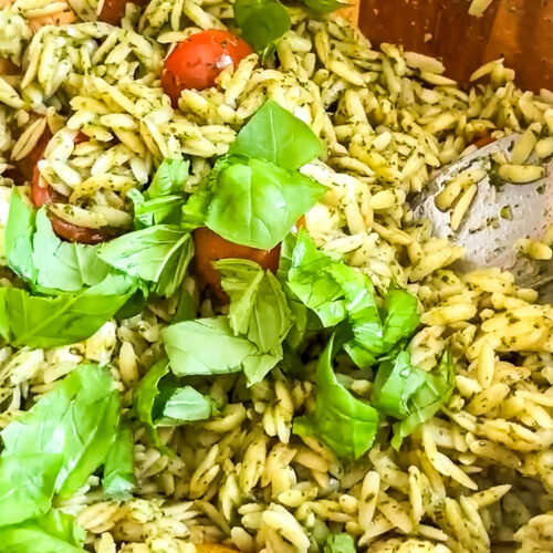 a close chose of orzo pesto salad with fresh basil