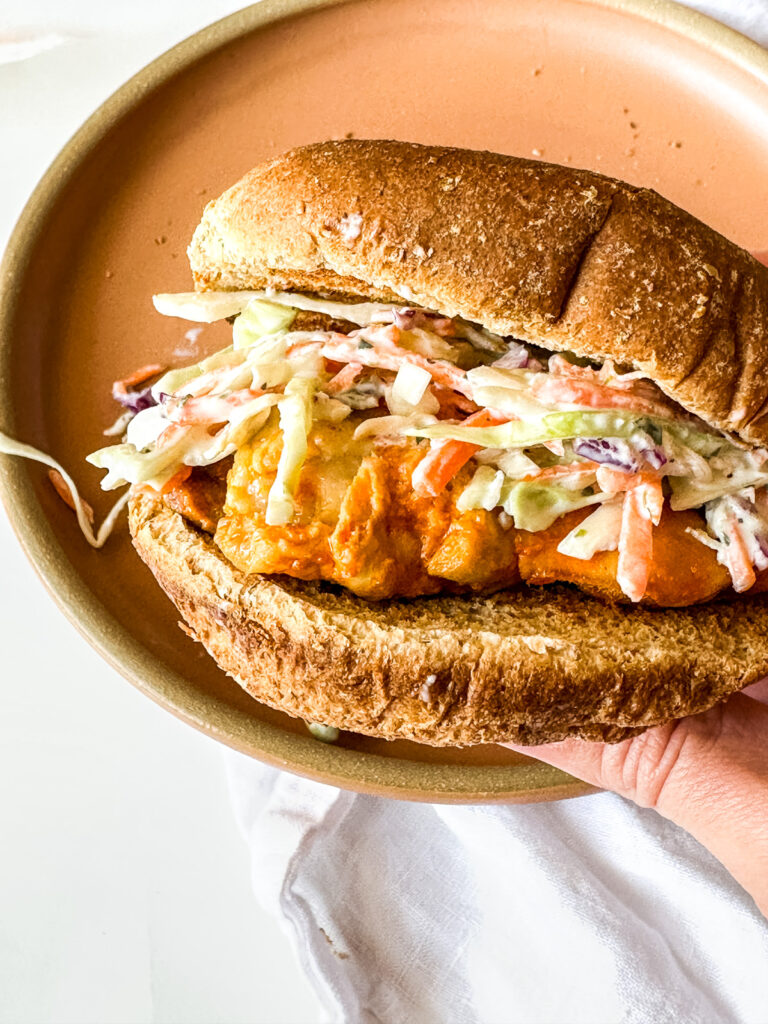 a sandwich with buffalo chicken thighs with coleslaw
