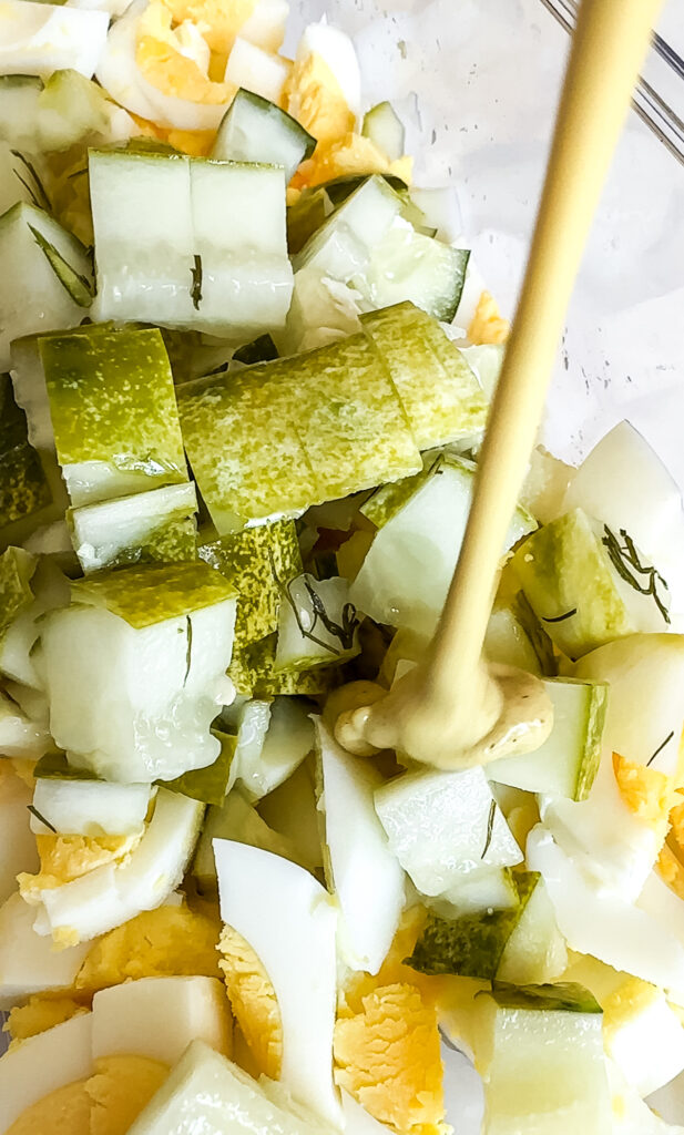 pouring mustard into egg salad